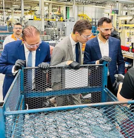 Visitors inspecting precision components in a production cell